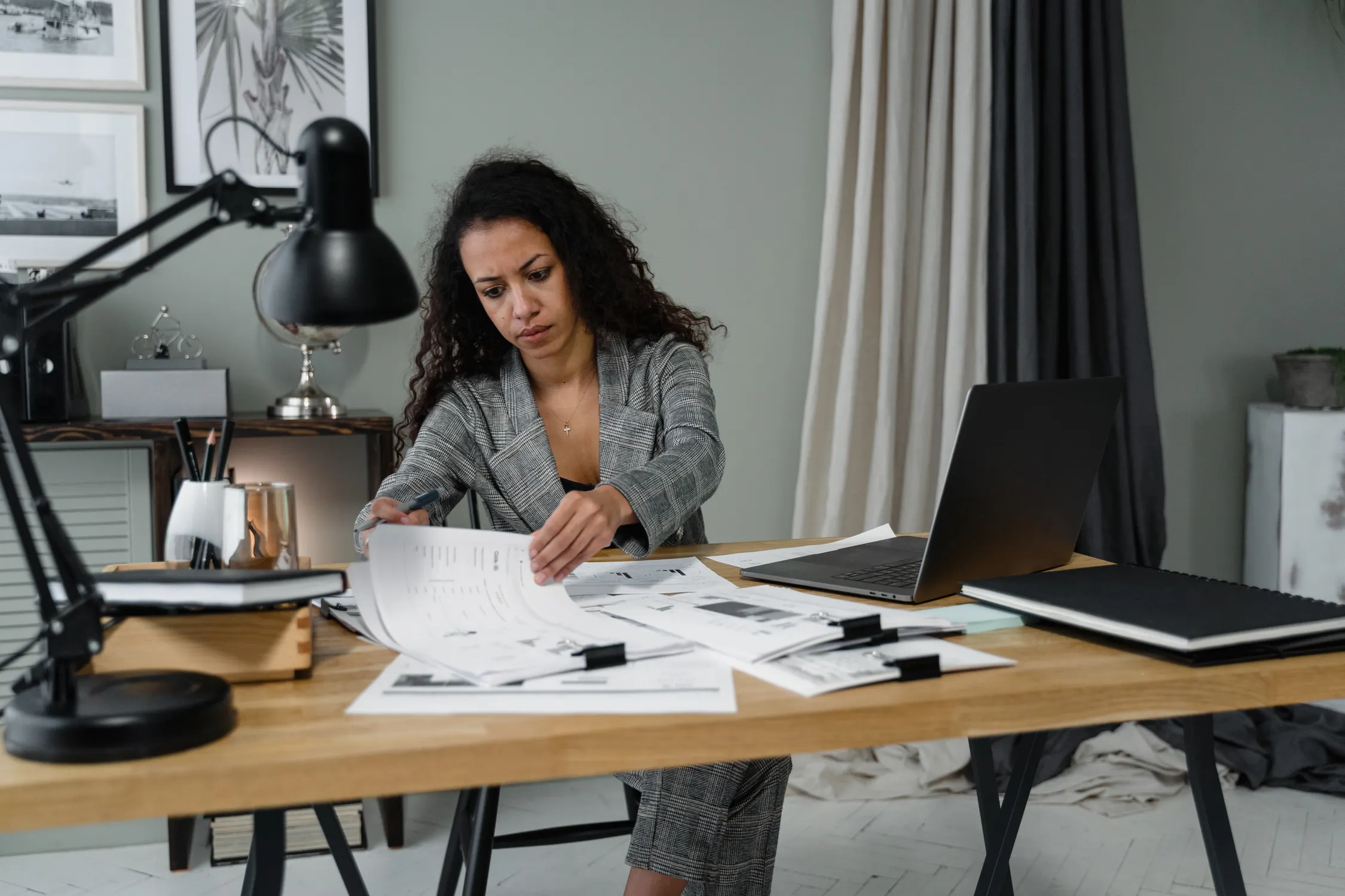 Tax professional reviewing financial documents at a desk with a laptop